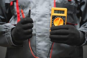Electrician with a multimeter in hands close up to show voltage measurement.